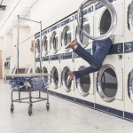 Person's legs hanging out of a washing machine in a laundromat